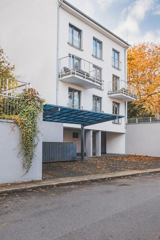 Metall-Carport an der Straße vor einem modernen Mehrfamilienhaus