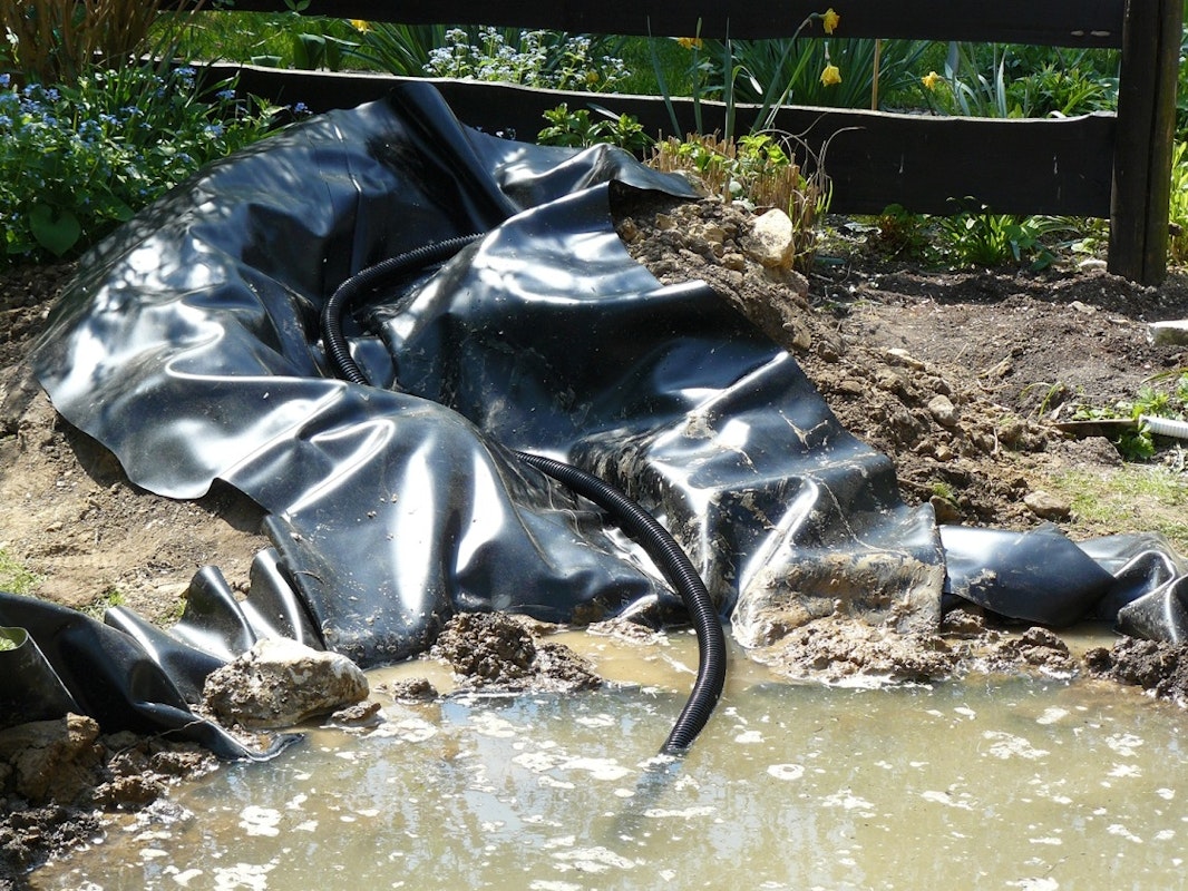 Teichbau Schritt 7: Der Bachlauf wird mit Teichfolie ausgelegt. Der Bachlauf wird mit Teichfolie ausgelegt.