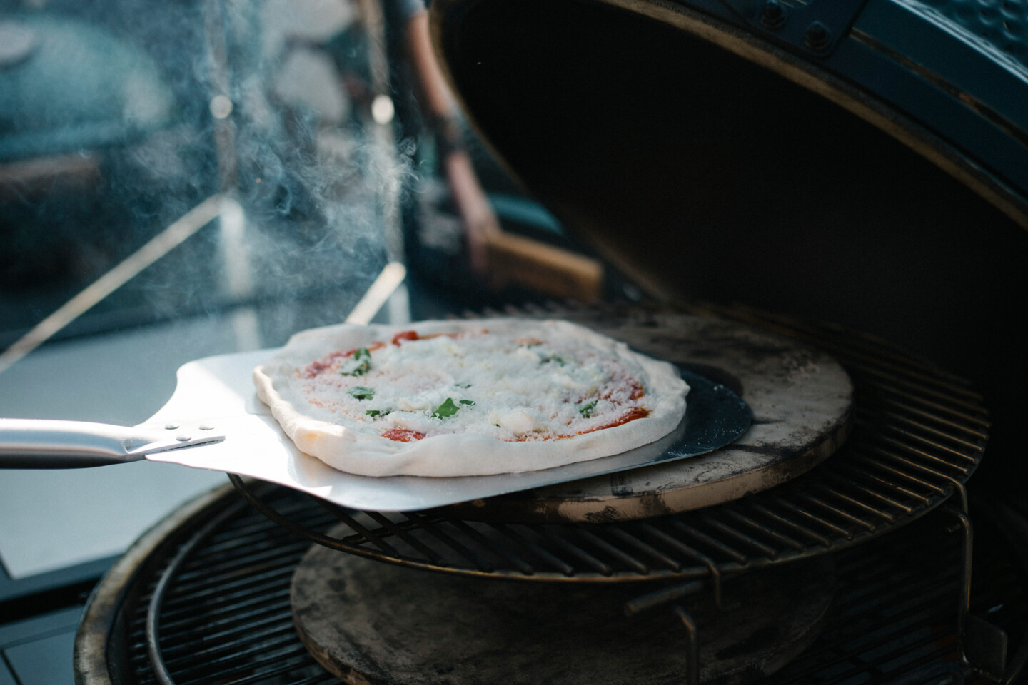 Die fertig belegte Pizza wird mit der Pizzaschaufel auf den Pizzastein gelegt
