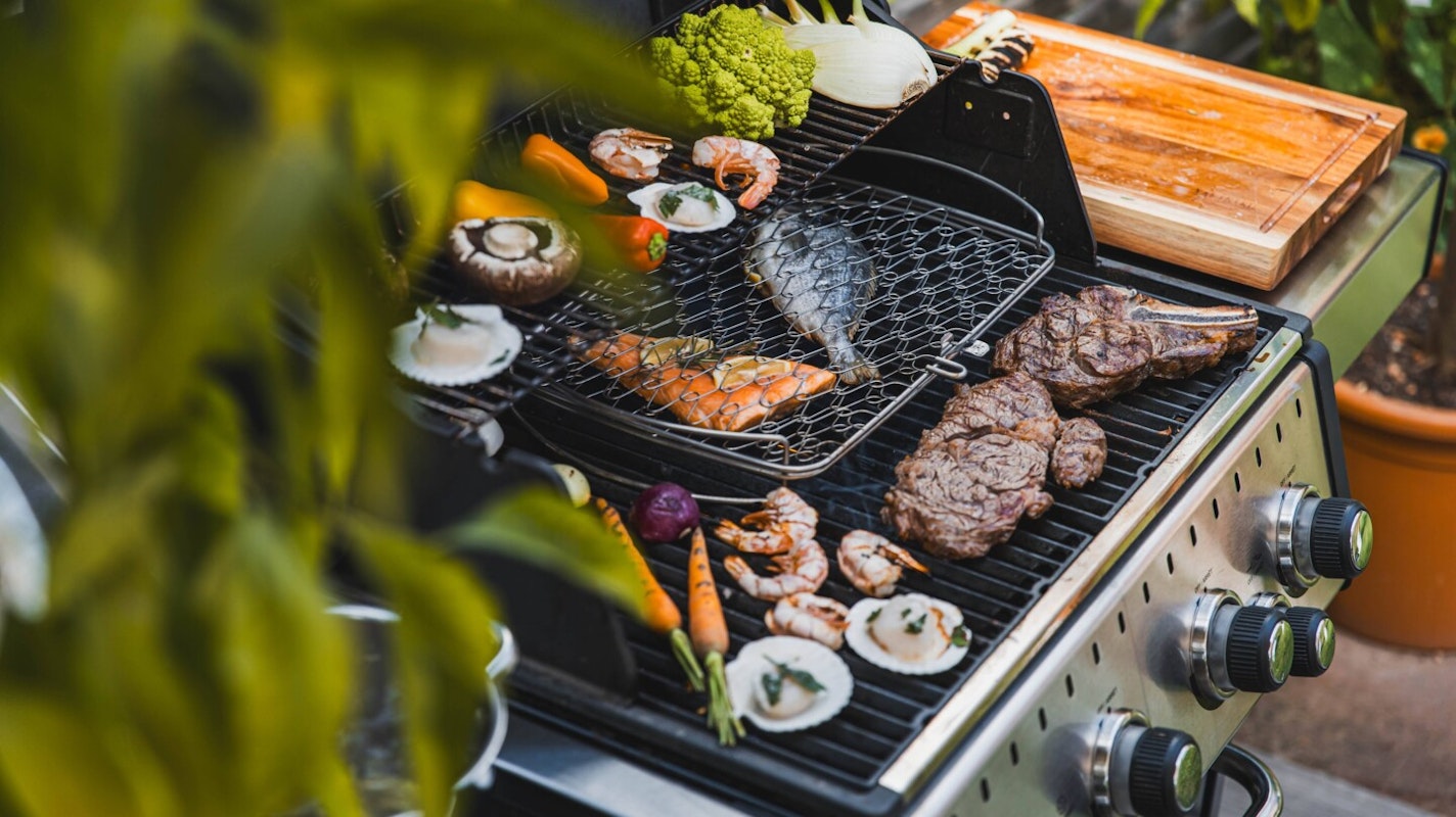 Nach dem Grillen ist vor der Grillreinigung Ein mit unterschiedlichsten, leckeren Speisen belegter Gasgrill. Doch nach dem Essen wartet das Putzen...