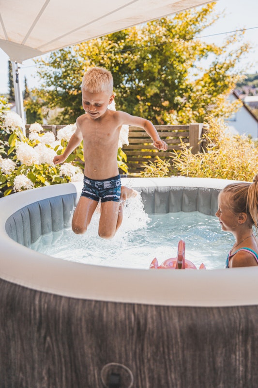 Badespaß im Whirlpool Kinder spielen in einem Whirlpool auf der Terrasse
